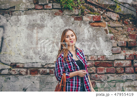 Beautiful girl is standing against brick wall 47955419