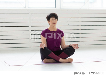 Healthy lifestyle, people and sport concept - Attractive middle age woman practicing yoga in lotus 47956809