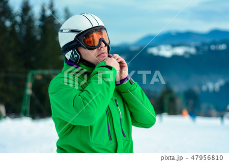 A man skier wearing a helmet and sunglasses before training for safety 47956810