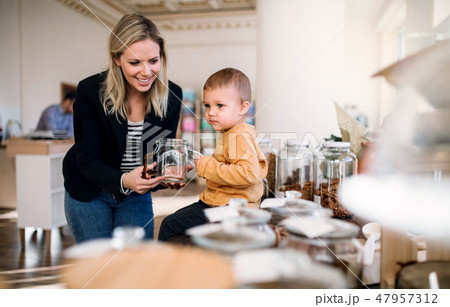 A young woman with a toddler boy buying groceries in zero waste shop. A young woman with a toddler boy buying groceries in zero waste shop. 47957312