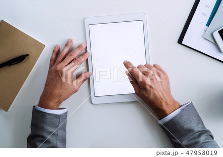 A midsection of businessman sitting at the table, using tablet. A top view. Copy space. A midsection of businessman sitting at the table, using tablet. A top view. Copy space. 47958019