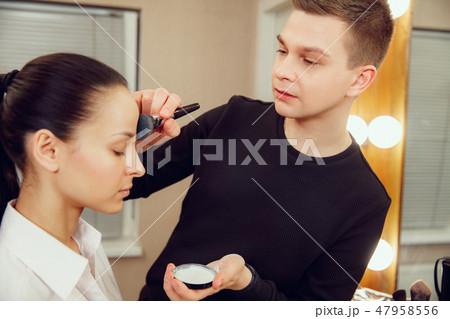 Professional makeup artist working with beautiful young woman Professional makeup artist working with beautiful young woman 47958556