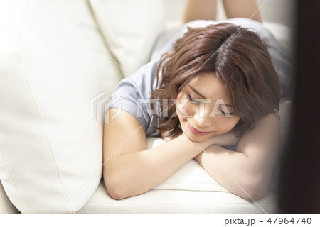 若い女性　ソファー　リラックス　ほおづえ　ライフスタイル 47964740