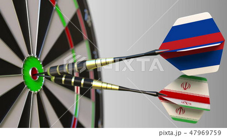 Flags of Russia and Iran on darts hitting bullseye of the target. International cooperation or 47969759