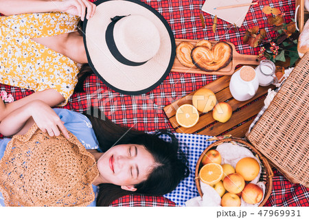 female friends enjoying picnic together in a park. female friends enjoying picnic together in a park. 47969931
