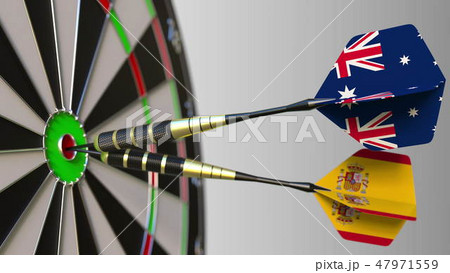 Flags of Australia and Spain on darts hitting bullseye of the target. International cooperation or Flags of Australia and Spain on darts hitting bullseye of the target. International cooperation or 47971559