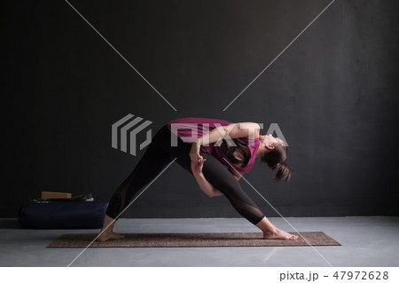 Girl standing in Utthita Trikonasana, extended triangle pose. 47972628