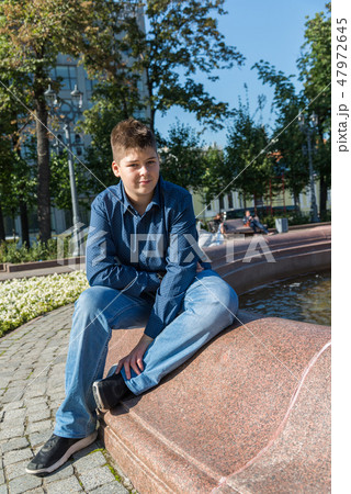 Teenager of 14 years is sitting near fountain 47972645