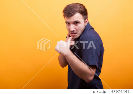 Agressive young man showing fists on yellow background 47974442
