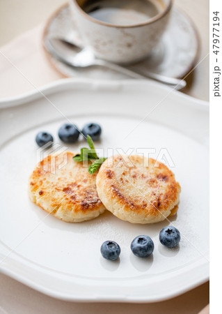 Cottage cheese pancakes or syrniki with blueberry on white plate, closeup view. Russian, Ukrainian Cottage cheese pancakes or syrniki with blueberry on white plate, closeup view. Russian, Ukrainian 47977194
