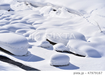 冬の北海道八雲町八熊峠の峠下で遊楽部川の河原の岩に大雪が積もりモコモコした風景を撮影 47979167