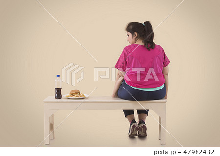Overweight Woman is looking at the hamburger Overweight Woman is looking at the hamburger 47982432