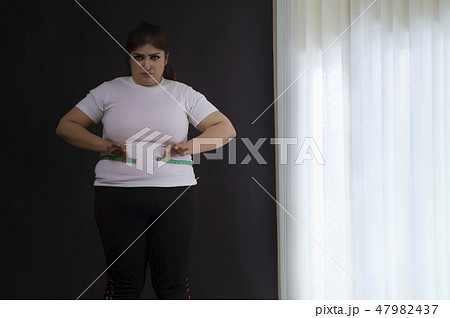 woman measuring her waist with a tape measure woman measuring her waist with a tape measure 47982437
