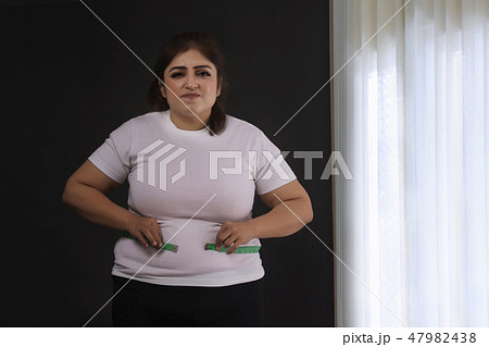 woman measuring her waist with a tape measure 47982438