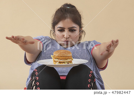 Overweight Woman Exercising with Burger Overweight Woman Exercising with Burger 47982447
