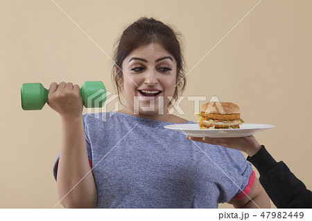 Woman Exercising Cropped Hand Giving Burger Woman Exercising Cropped Hand Giving Burger 47982449