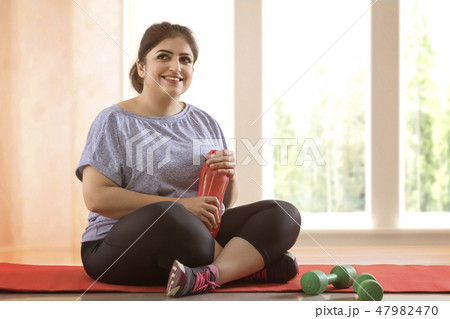 Overweight woman taking a break from exercising Overweight woman taking a break from exercising 47982470