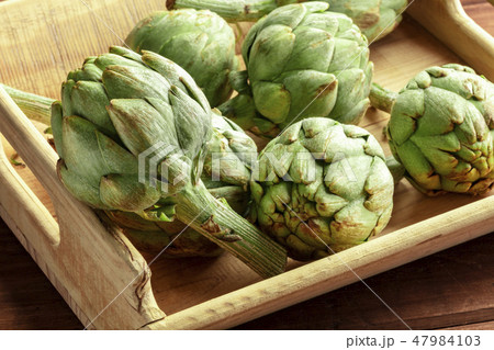 A closeup of a globe artichoke in a wooden crate A closeup of a globe artichoke in a wooden crate 47984103