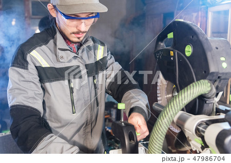 A young male carpenter installs a workpiece in a circular machine. Handwork. Starting a business A young male carpenter installs a workpiece in a circular machine. Handwork. Starting a business 47986704
