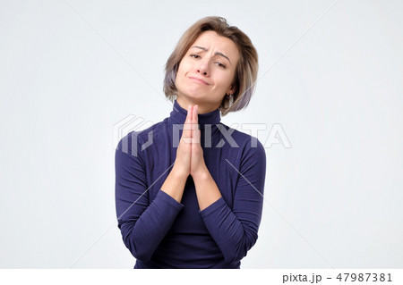 Woman holding palms pressed together in front of her, asking for forgiveness Woman holding palms pressed together in front of her, asking for forgiveness 47987381