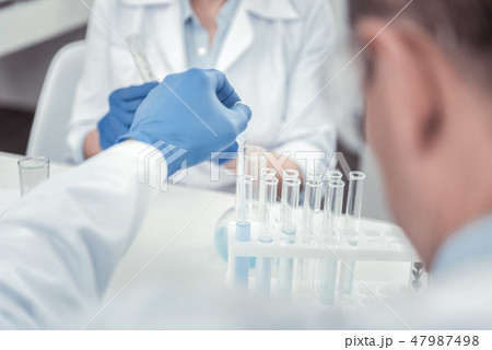 Scientist putting liquids tnto test tubes with pipette Scientist putting liquids tnto test tubes with pipette 47987498