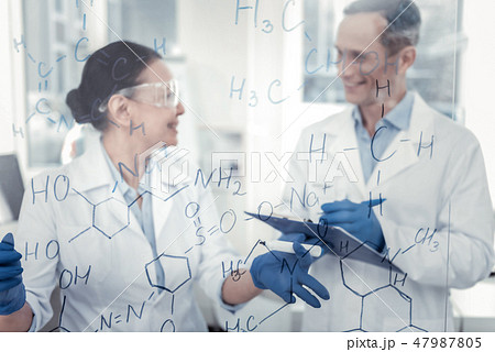 Qualified scientists discussing chemical formulas on the board Qualified scientists discussing chemical formulas on the board 47987805