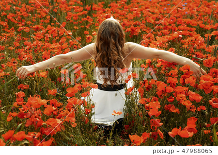 Beautiful young woman in poppy field with flying hair Beautiful young woman in poppy field with flying hair 47988065