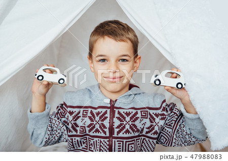 smiling child in pajamas holding two wooden car toys smiling child in pajamas holding two wooden car toys 47988083