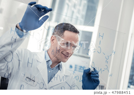 Smiling scientist figuring out new chemical formula Smiling scientist figuring out new chemical formula 47988451