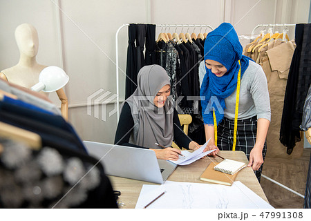 Muslim woman designer team discussing dress sketch 47991308