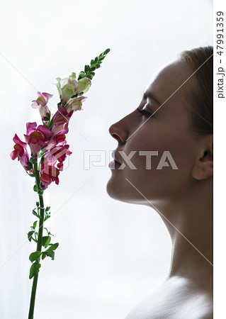 Face of young girl in profile sniffing flower 47991359