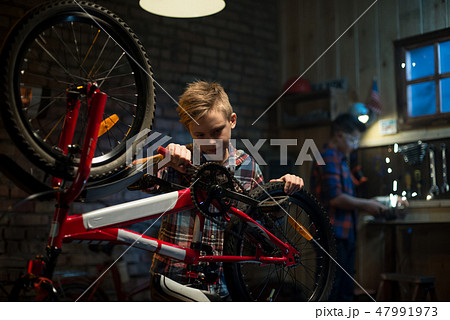 Two boys repairing a bike in a garage Two boys repairing a bike in a garage 47991973