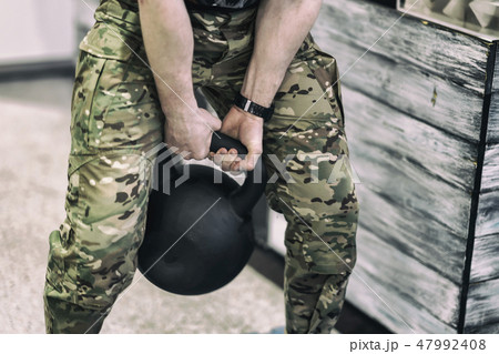 Abstract athlete in camouflage pants with weights, lifting a heavy weight 47992408