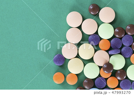 Multi-colored pills on a green background Multi-colored pills on a green background 47993270