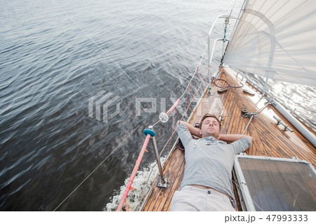young european man resting on yacht looking at sky young european man resting on yacht looking at sky 47993333