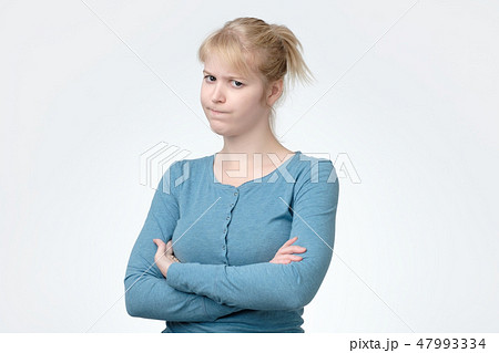 Upset unsatisfied blonde woman standing with arms folded Upset unsatisfied blonde woman standing with arms folded 47993334