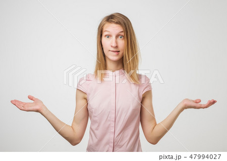 Shrugging european woman wearing pink shirt in doubt doing shrug 47994027