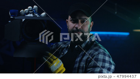 Cameraman holding a Fresnel lamp 47994437