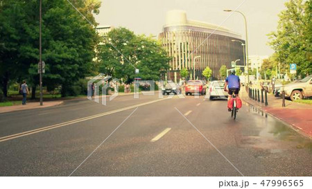 Man riding his bicycle along European city car road 47996565