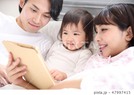 ベッドに入る若い家族 47997415