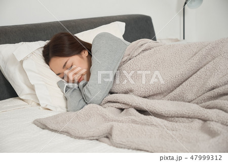 ベッドで寝ている女性 47999312