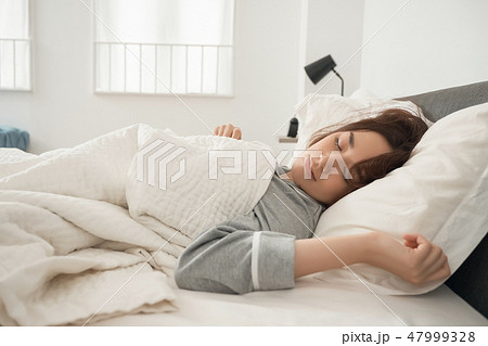 ベッドで寝ている女性 47999328