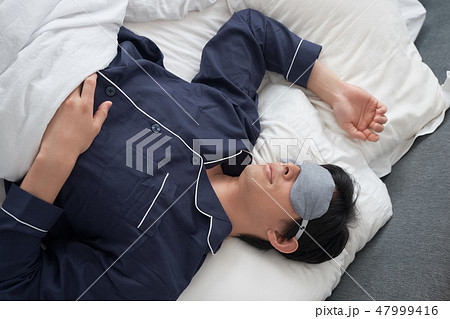 ベッドで寝ている男性 47999416