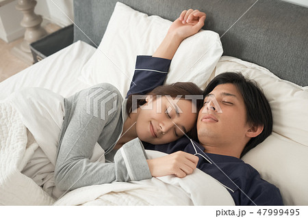 ベッドで寝ている夫婦 47999495