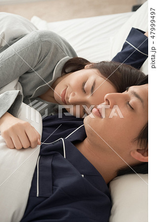 ベッドで寝ている夫婦 47999497