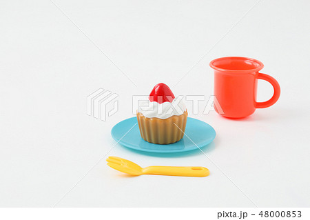 白背景に子供の遊ぶおもちゃケーキカップとコップの写真素材