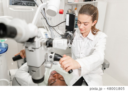 Female dentist advanced user, dental tools. Setup microscope for examining his patients teeth. in 48001805