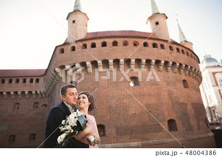 Happy wedding couple, groom, bride with pink dress hugging and smiling each other on the background 48004386