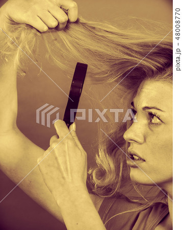 Woman looking at hair through magnifying glass Woman looking at hair through magnifying glass 48008770