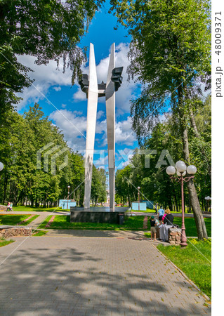 A commemorative sign in a park with resting people 48009371